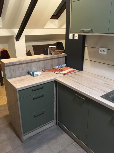 Moderne keuken met groene kasten en houten werkblad.