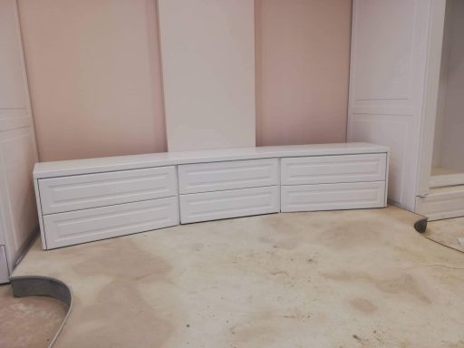 Witte kasten met lades, geplaatst in een hoek van een kamer.