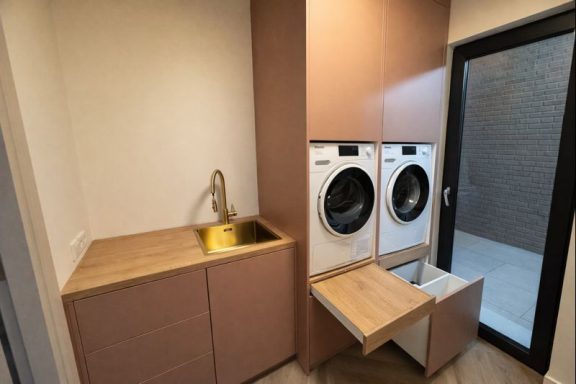 Moderne wasruimte met een wasmachine, droger en een gootsteen in een minimalistisch design.