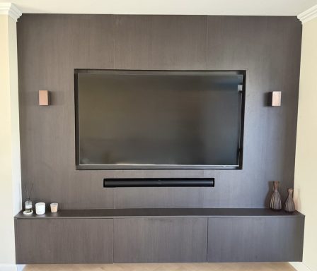 Donker houten wand met een televisie, wandplanken en decoratieve vazen.