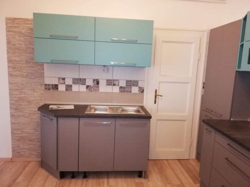 Moderne keuken met blauwe kastjes, twee spoelbakken en gemêleerde wandtegels.