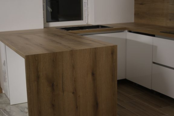 Moderne keuken met een houten aanrechtblad en witte kasten.