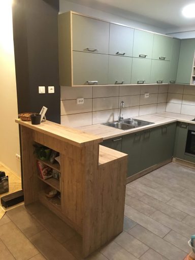 Moderne keuken met houten bar en groene bovenkasten.