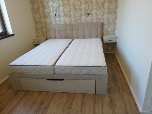 Een tweepersoonsbed met losse matrassen in een eenvoudig ingerichte kamer.
