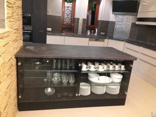 Moderne keuken met een glazen kast, borden en glazen op een eiland.