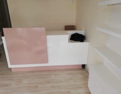 Een moderne receptie met een witte en roze afwerking, naast een witte wand.